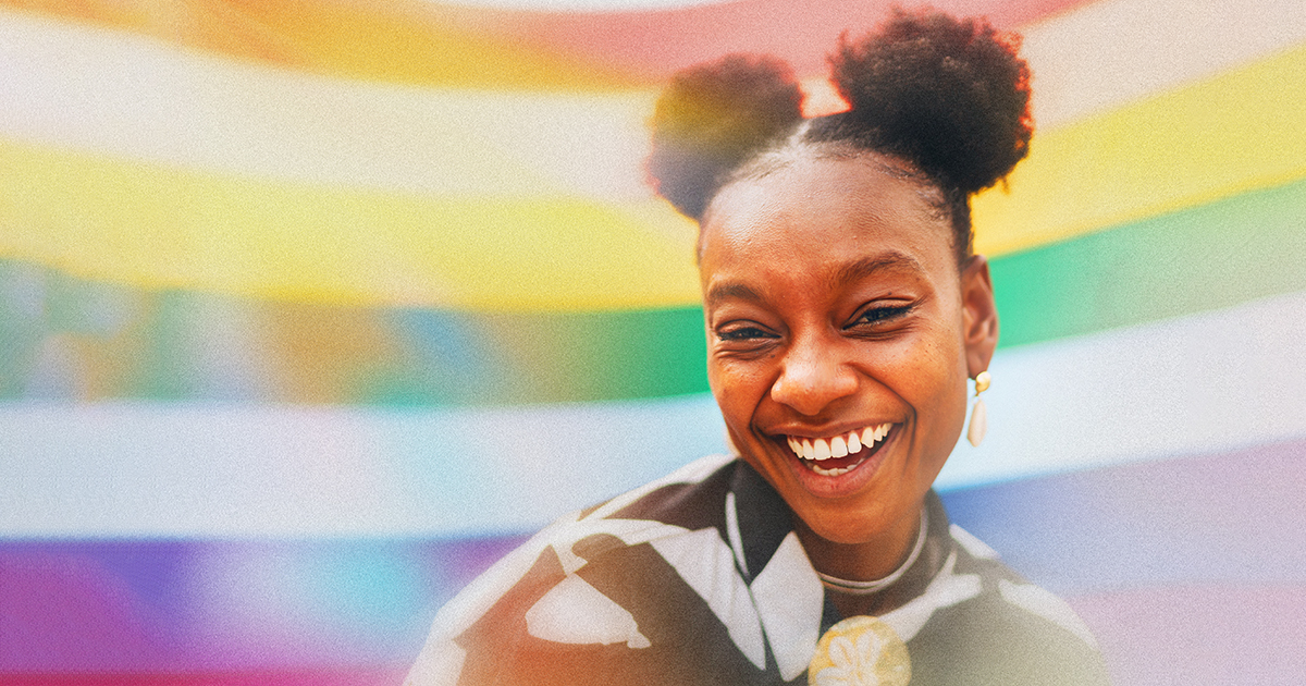 Girl with space buns in front of a pride flag
