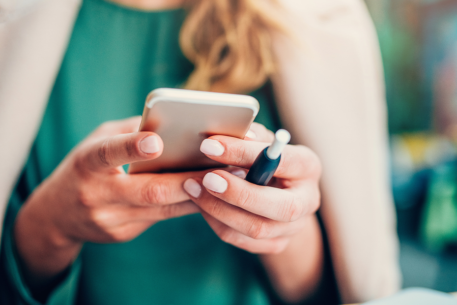 Woman holding an IQOS and a Cell Phone