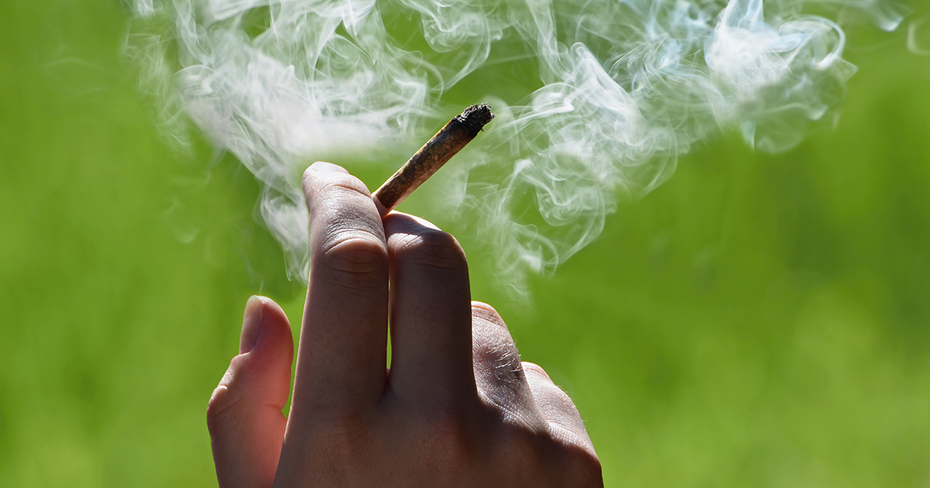 Hand holding a lit marijuana joint