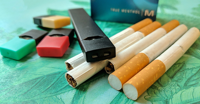 JUUL pods and a JUUL laying on cigarettes