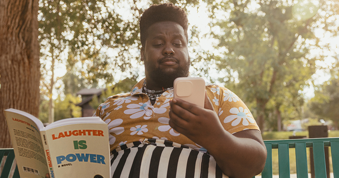 Black male reading a book and looking at his cellphone
