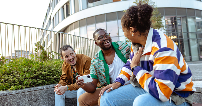 Young adults sitting on a bench laughing