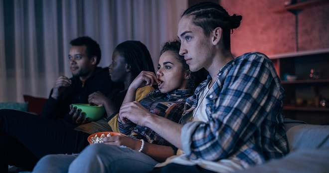 Young adults watching a movie and eating popcorn