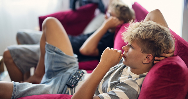 Two guys watching streaming on a red couch