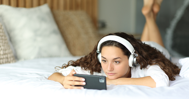Young woman streaming on her phone on the bed